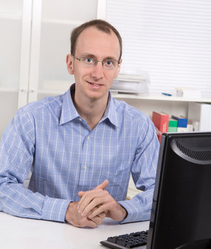 Portrait: Gesch&auml;ftsmann in Hemd blau sitzend im B&uuml;ro