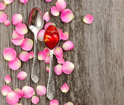 Two spoons with red heart on wooden background