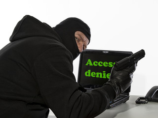 Einbrecher mit Pistole vor Laptop