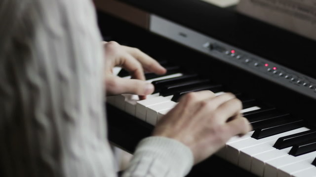 pianist's fingers press the keys on the synthesizer