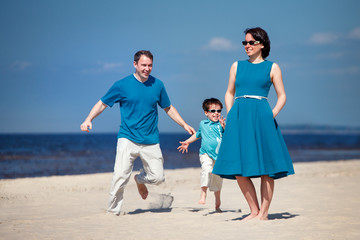 Young family of three having fun tropical beach