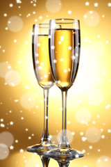 Two glasses of champagne on bright background with lights