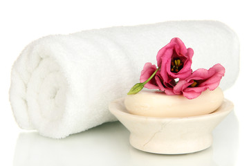 Fototapeta na wymiar Walcowane białe ręczniki, mydła i piękny kwiat samodzielnie