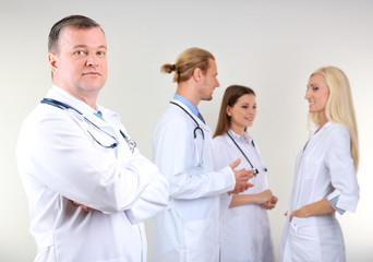 Doctor standing in front of coworkers on grey background