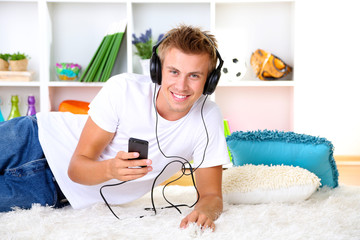 Young man relaxing on carpet and listening to music