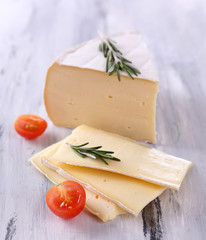 Tasty Camembert cheese with tomato and rosemary, on wooden
