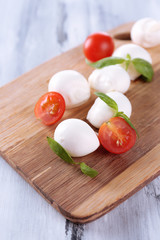 Tasty mozzarella cheese with basil and tomatoes, on wooden