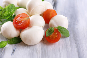 Tasty mozzarella cheese with basil and tomatoes, on wooden