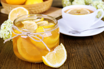 Tasty lemon jam with cup of tea on table close-up