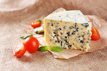 Tasty blue cheese with tomatoes and basil, on burlap background