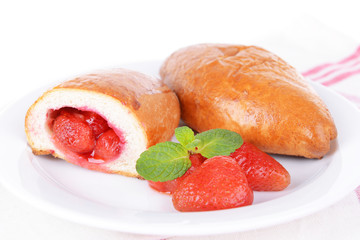 Fresh baked pasties with strawberries on plate on table