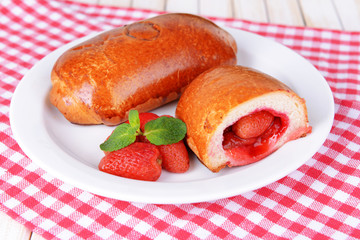 Fresh baked pasties with strawberries on plate on table