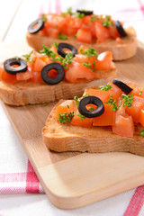 Delicious bruschetta with tomatoes on cutting board close-up