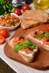 Delicious bruschetta with tomatoes on cutting board close-up