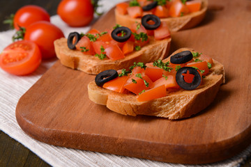 Delicious bruschetta with tomatoes on cutting board close-up