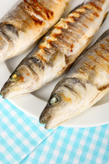 Delicious grilled fish on plate on table close-up