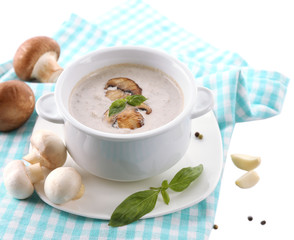 Mushroom soup in white pot, on napkin, isolated on white