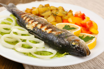 Delicious grilled fish on plate on table close-up