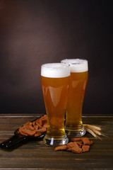 Glasses of beer with snack on table on dark background