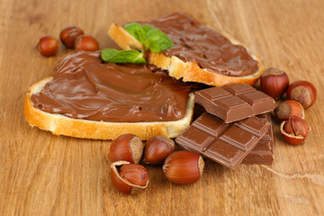 Bread with sweet chocolate hazelnut spread on wooden background