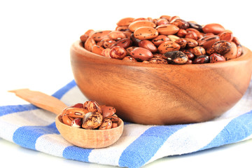 Raw beans in bowl on color napkin, isolated on white