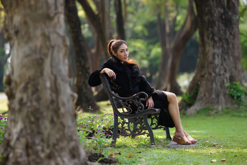 Beautiful Asian lady in black dress, posing in the park, greener