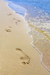 Footprints on the beach by the sea.