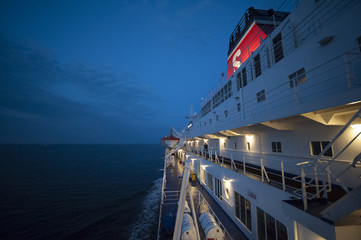 Fragment of a ferry in the sea at night, with illuminated decks
