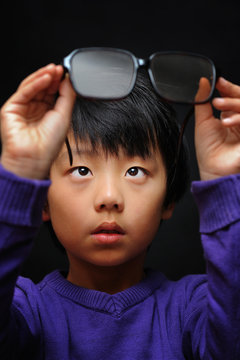 Asian boy with bad eyesight trying his new glasses