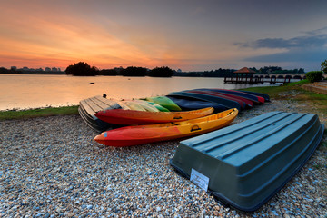 Fototapeta premium A bunch of kayaks and boat stranded with a sunset view.
