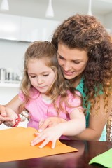 Naklejka premium Little girl making paper shapes with mother at the table