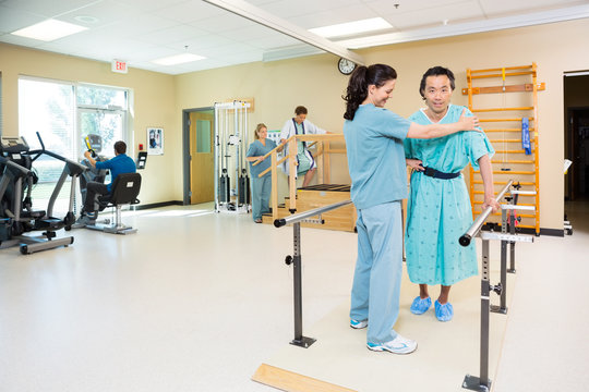 Therapists Assisting Patients In Hospital Gym