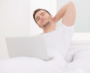 handsome man sitting in bed and working.