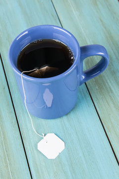 Taza de t&eacute; sobre fondo de madera zul con etiqueta en blanco
