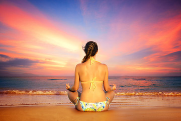 Woman in lotus position on a background of sunset