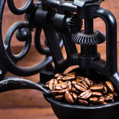 Vintage manual coffee grinder with coffee beans on wooden brown