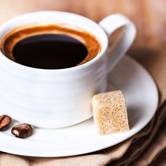 Coffee cup with white saucer and roasted coffee beans  on wooden