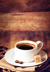 Cup of coffee with coffee beans on a beautiful wooden  brown bac