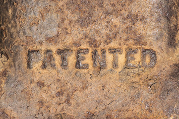 Old weathered rusty cast iron surface labeled "patented"