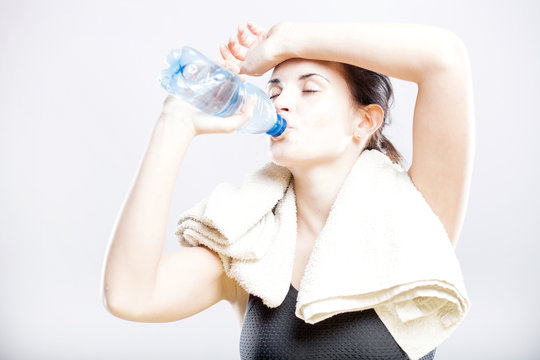 Young fit woman drinking water after fitness