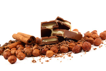 Stack of chocolate tiles with hazelnuts and cinnamon sticks.