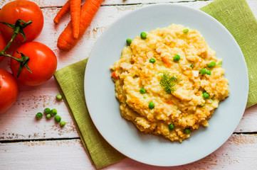 Rice with vegetables and chicken on white wooden background