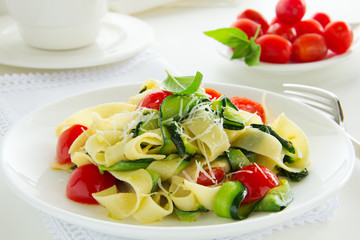 Pasta tagliatelle with zucchini and tomatoes.