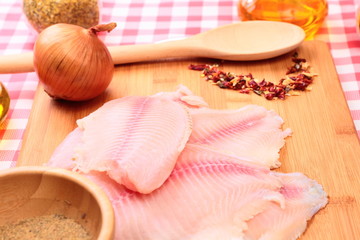 Raw fish tilapia on cutting board and spices
