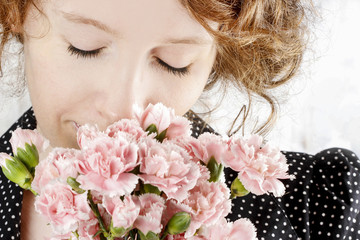 Beautiful young woman holding bouquet of pink carnation