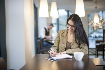 smart woman writing in a cafe