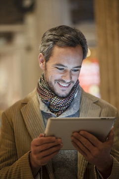 handsome man using a digital tablet outside with city lights at