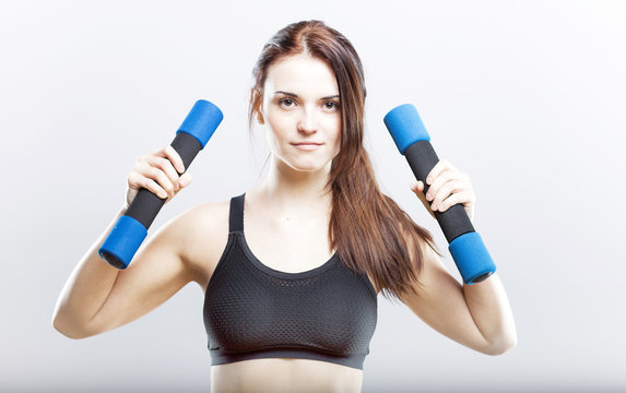 Young fit woman training with dumbbells