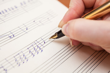 Hand with pen and music sheet