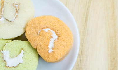 close up  slice roll cake on white plate on wood background